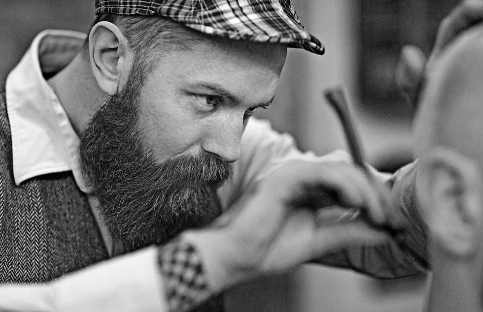 Stylish retro bearded barber with a bald male client
